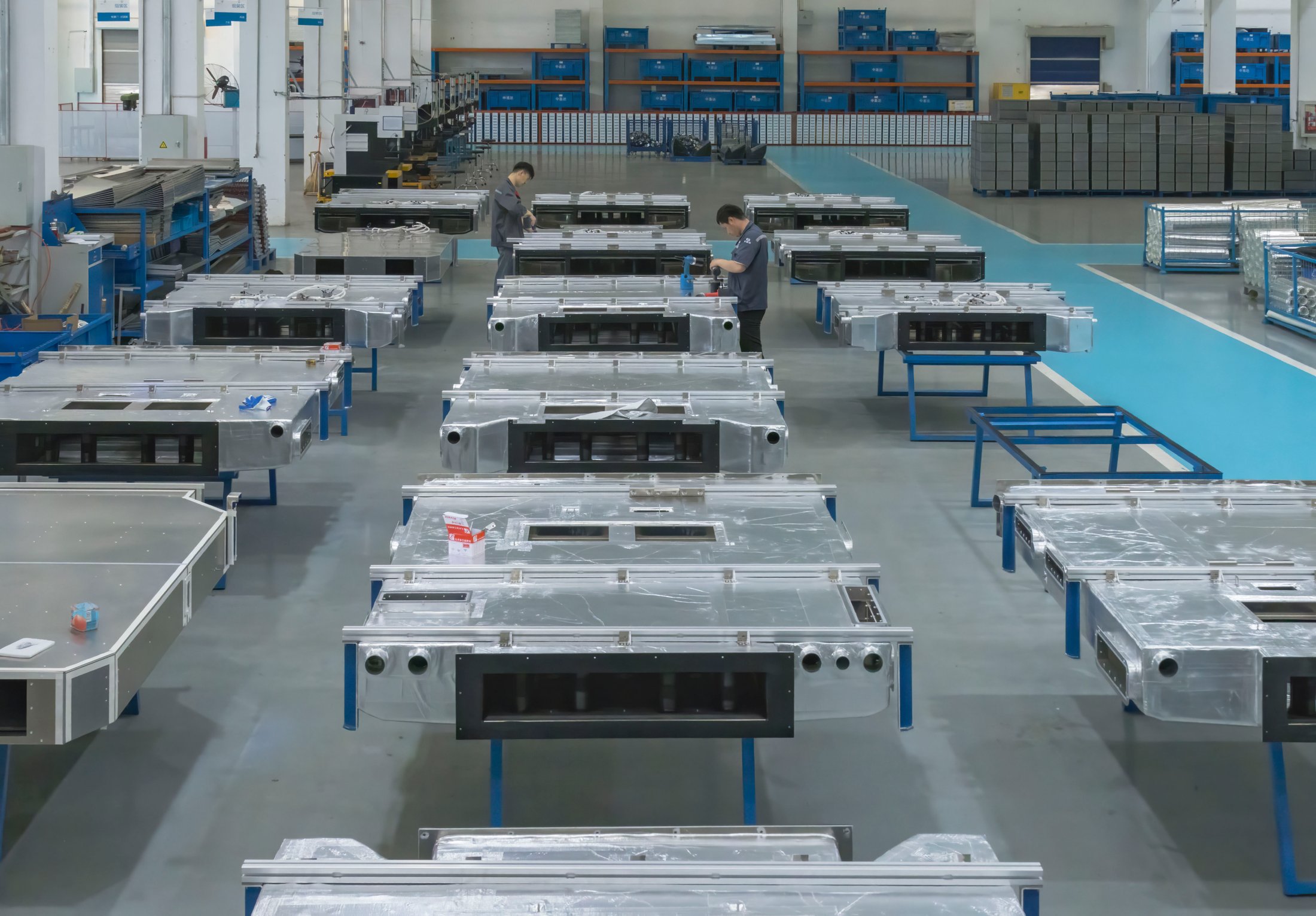 ZJD workshop with rows of fabricated metal assemblies and workers at assembly stations